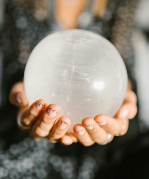 Close-up of hands holding a clear crystal ball, ideal for spiritual or metaphysical themes.