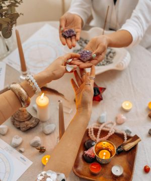 A serene indoor setting with hands exchanging healing crystals, surrounded by candles and spiritual items.